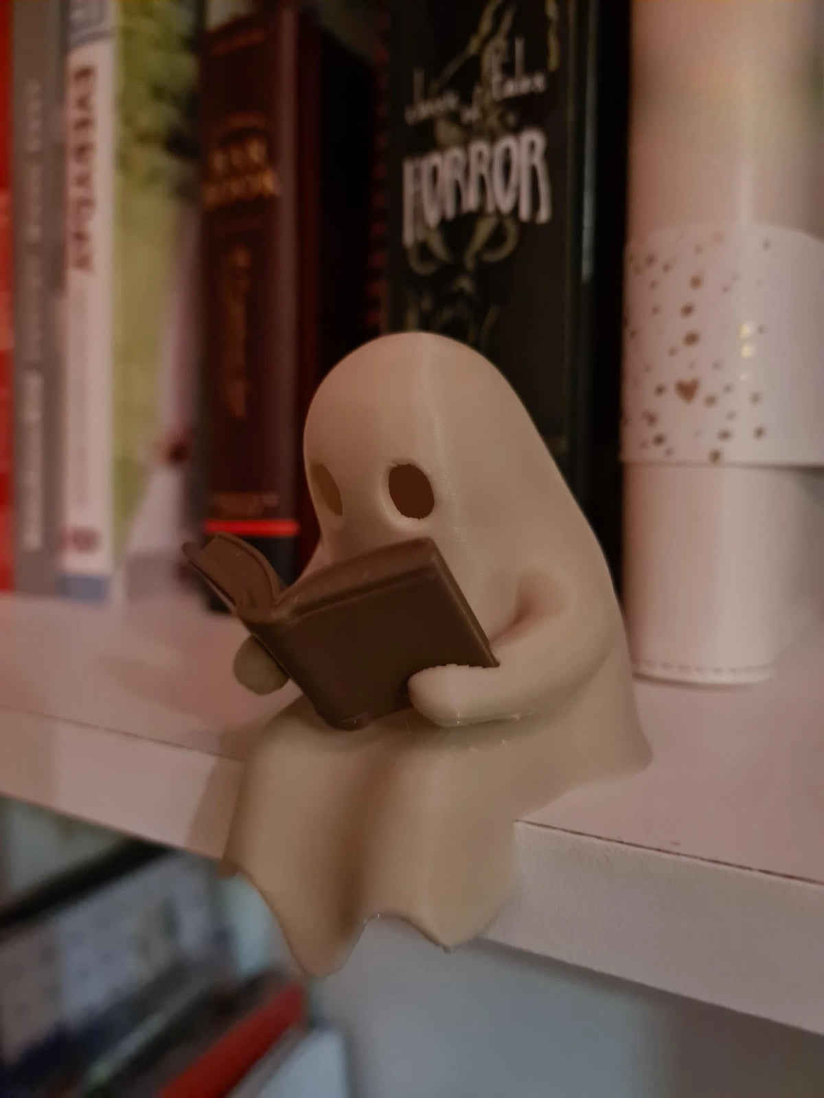 Cute Little Ghost Sitting on A Shelf Reading A Book with Flickering Ornament