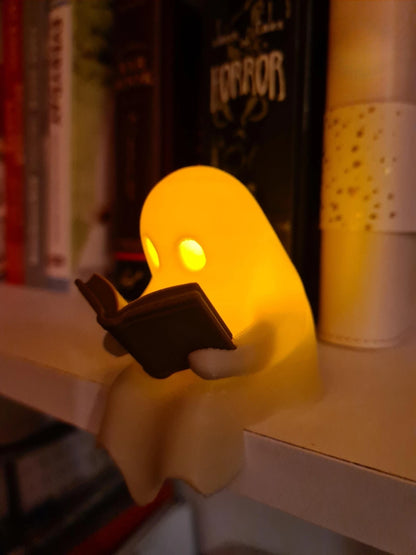 Cute Little Ghost Sitting on A Shelf Reading A Book with Flickering Ornament